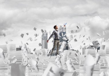 Sıradan giyinen bir adam kitapla el ele tutuşurken arka planda şehir manzarası olan uçan kağıt belgelerin arasında dikiliyor. Karışık ortam.