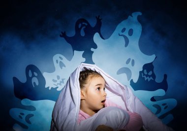 Hayali hayaletlerden battaniyenin altına saklanan heyecanlı kız. Evde yatağında oturan korkmuş bir çocuk. Küçük kız fantezi canavarlar korkuyor. Pijama kaplı çocuk geceleri uyumaz. Cadılar Bayramı tatili.