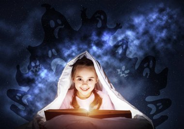 Mutlu küçük kız uyumadan önce yatakta kitap okuyor. Battaniyenin altında el feneri saklanan bir çocuk. Pijama ve komik hayaletler gece gökyüzünde geri gülümseyen kız. Çocuk okuma sihirli peri masalları.