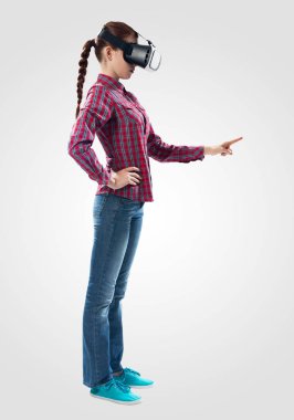 Sanal gerçeklik gözlüğü kullanan güzel kız. Vr gözlüğü takan kadın işaret jestini kullanarak siber alemle etkileşime giriyor. Gri arka plan karşı kız tarafından Stüdyo fotoğrafı. Siber teknoloji konsepti