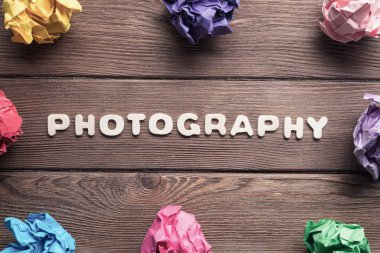 Ahşap masa üzerinde daire içine yerleştirilmiş renkli kağıt toplar.