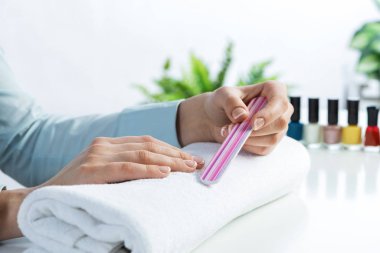 Kadın tırnak törpüsü kullanıyor ve mükemmel tırnak şekli yaratıyor. Tırnak törpüleme aleti ile kadın tırnaklarını törpülemek ve oje sürmeye hazırlanmak. Evde tırnak bakımı yapan bir kadın. Güzellik ve temizlik.