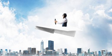 Megapolis'in üstünde kağıt uçak kullanan havacı. Kağıt düzlemde oturan ve direksiyon u tutan pilotun yan görünümü. Yüksek gökdelenler ve ofis binaları ile Cityscape. Karma medya iş kavramı