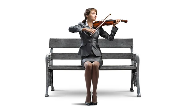 年轻女子用小提琴在木凳上 穿着西装的漂亮女孩坐在长凳上 放着乐器 女商人在白色背景上单独拉小提琴 音乐家表演 — 图库照片