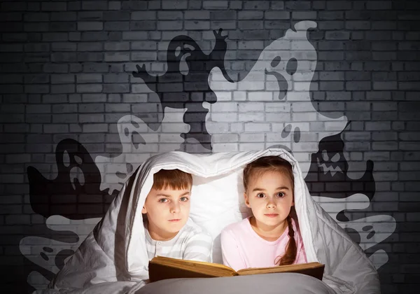 귀여운 소녀와 침대에서 손전등을 아이들은 아래에 잠옷과 재미있는 실루엣을 동화를 — 스톡 사진