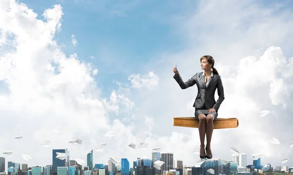 Mädchen im Businessanzug fliegt in blauem Himmel großes Buch — Stockfoto