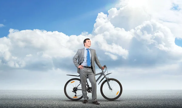 Confident and successful man in business suit standing with bike. Businessman with bicycle on background of blue sky. Male cyclist posing on camera with bicycle. Man relaxing outdoors in sunny day.