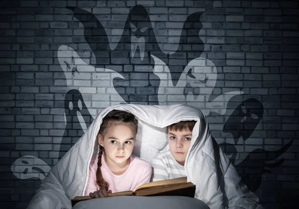 귀여운 소녀와 침대에서 손전등을 아이들은 아래에 잠옷과 재미있는 실루엣을 동화를 — 스톡 사진