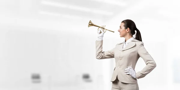 トランペットを吹く実業家 白いビジネススーツの若い女性と光のオフィスのインテリアで楽器をポーズ手袋 音楽家とのビジネス支援とサポートの概念 — ストック写真