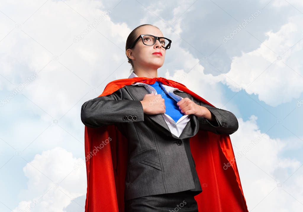 Portrait of business woman super heroine. Attractive young business lady in suit with red cloak on blue sky background. Successful and confident super woman in glasses ready for new challenges.