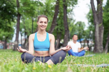Kız nilüferde meditasyon yapıyor yeşil çimlerde poz veriyor. Yaz parkında yoga pratiği yapıyorum. Huzurlu genç bir kadının portresi. Yaz günü dışarıda antrenman ve meditasyon. Sağlıklı yaşam tarzı ve rahatlama.