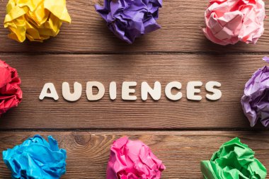 Ahşap masa üzerinde daire içine yerleştirilmiş renkli kağıt toplar.