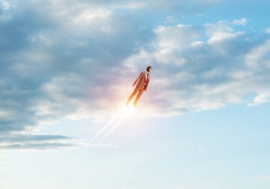 Havacı şapkalı bir iş adamı bulutlu mavi gökyüzünde süper kahraman olarak uçuyor. Jet alevleri ile uçan gezegen atmosferinde süper kahraman olarak çalışan iş adamı. Gol başarı konsepti. Kariyer hırsı ve büyüme.
