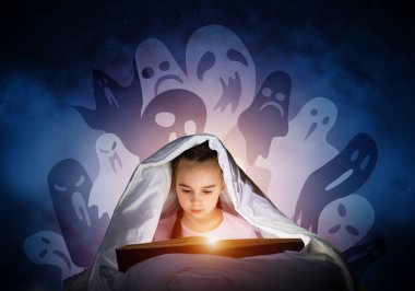 Dalmış küçük kız yatmadan sonra yatakta kitap okuyor. Battaniyenin altında el feneri olan pijamalı çocuk. Korkulu kız ve derin mavi arka plan üzerinde hayali canavarlar. Çocuk masalları okuma.