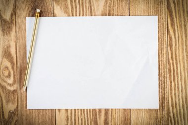 Boş kağıtlı, asgari ahşap masa işyeri. Beyaz a4 formatlı kalem kağıdı. Dokulu doğal ahşap arka plan. Yaratıcı tasarım ve reklam için klasik kopya alanı. İş planlaması