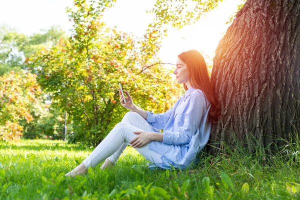 Jonge Roodharige Vrouw Met Smartphone Onder Boom Het Park Zonnige — Stockfoto