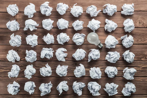 Bombilla Incandescente Bolas Papel Blanco Arrugadas Sobre Mesa Madera Marrón —  Fotos de Stock