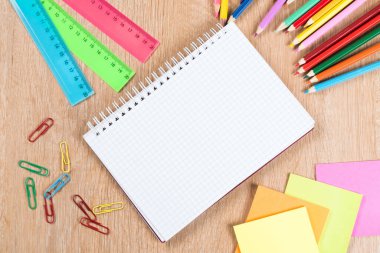 Ahşap yüzeyüzerinde boş not defteri çıkartmaları ve kalem ile okul konseptine geri dön