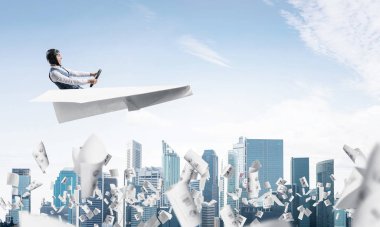 Havacı bulutlu mavi gökyüzünde iş merkezi üzerinde kağıt uçak sürüş. Gökdelenlerin arka planına düşen kağıtlar. Deri kasklı pilot kağıt düzlemde otururken ve direksiyonu tutarak.