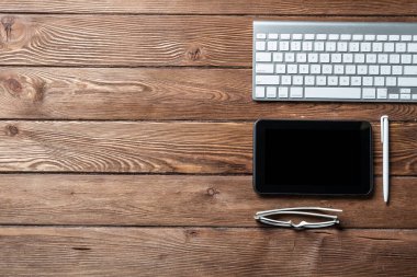 Aletlerle ofis çalışma alanının en üst görüntüsü. Klavye ve tablet bilgisayarlı düz ahşap masa. Çevrimiçi muhasebe ve bankacılık. İş dünyasında dijital teknoloji. Klasik kahverengi ahşap yüzey