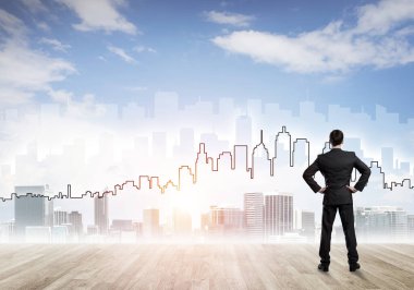 İşadamı arkasını dönüp modern iş merkezinin siluetine bakıyor.