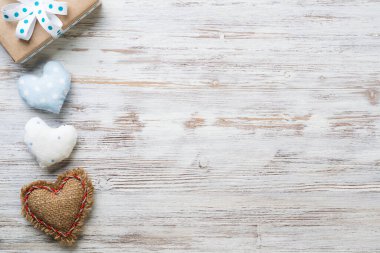 Düz, el yapımı kumaş kalplerle hoş bir kompozisyon sergiliyordu. Tahta masanın üzerinde kurdele yayı olan hediye kutusu. Doğum günün kutlu olsun ya da yıldönümün kutlu olsun. Kopyalama alanı olan romantik ileti şablonu.