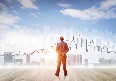 İşadamı arkasını dönüp modern iş merkezinin siluetine bakıyor.