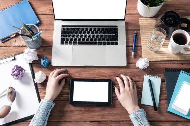 Ofis masasında çalışan bir iş kadını. Düz tahta masa, dizüstü bilgisayarı ve beyaz ekranlı tablet bilgisayarı vardı. Kadın eli ile üst düzey ofis işyeri. Çevrimiçi iş ve internet ticareti