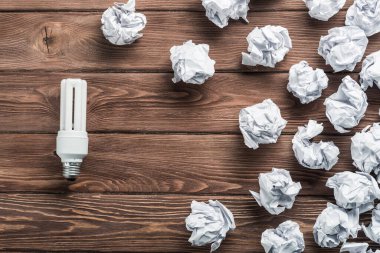 Akkor ampul ve buruşuk beyaz kağıt topları kahverengi ahşap tablo