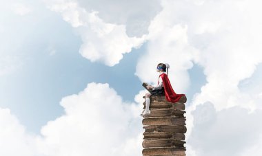 Küçük çocuk maskesi ve cape sittting yığın üzerinde eski gökyüzü ve okuma kitapları