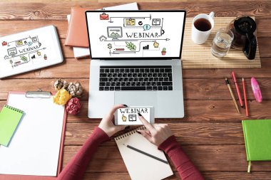 Kadın eli ile modern ofis çalışma alanı. Düz tahta masa, dizüstü bilgisayarlı klavye ve bir fincan kahve. İş kadını elleri bilgisayar modellemesinde çalışıyor. Bilgisayar ekranında giyim bilgisi grafikleri
