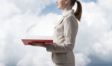 İş kadını, arka planda açık bir defter tutuyor. Profesyonel danışmanlık ve danışmanlık. Kapanış kitabı, kadın ellerinde kırmızı kapaklı. Beyaz takım elbiseli genç kadın..