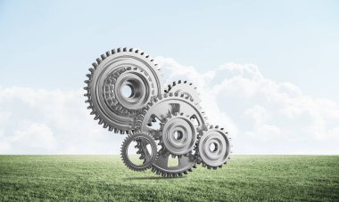 Yeşil çayır üzerinde cogwheels ile soyut mekanizma. İnşaat ve üretim. Mekanik teknoloji makine mühendisliği. Yeşil çimen ve mavi gökyüzü ile doğa manzara. 3b nesneile karışık ortam