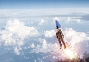 Takım elbiseli ve pilot şapkalı bir işadamı stratosferde roket üzerinde uçuyor. Bulutların üstünde mavi gökyüzünde jetpack roketiyle uçan süper kahraman iş adamı. Başarılı bir iş girişimiydi. Kariyer gelişimi konsepti.