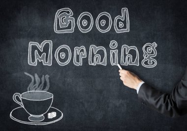 Tebeşirle çalışan iş adamı tahtaya günaydın çizimi çizer. Tahtada serbest beyaz tebeşir çizimi. Bir fincan sıcak içecek ve çay tabağı. Sabah kahvaltısı ve kahve molası.