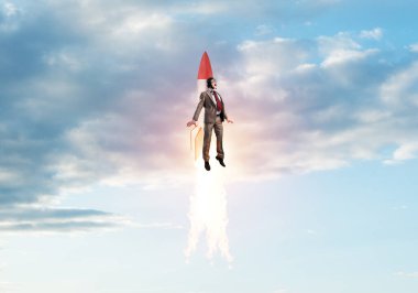 Havacı şapkalı bir iş adamı roketle uçuyor. İlerleme ve yenilik teknolojisi. Bulutların üstünde mavi gökyüzünde jetpack roketiyle uçan şirket işadamı. Liderlik motivasyon kavramı.