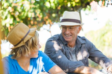 Senior man share its experience with guy in vineyard. People relationships and communication concept. Winegrower man in straw hat speaking with boy. Two generations of vintners together. clipart