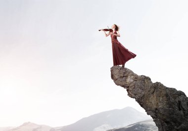 Keman ayakta rock üst kısmında oynayan genç çekici kız