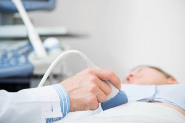 Sonograf iş yerinde ultrason makinesi kullanıyor. Modern klinik tanı ve tedavi. Doktorun elinde ultrason tarayıcısı var. Doktor ultrason hastanede kadın hasta karnını muayene ediyor..
