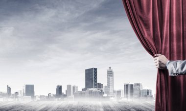 İnsan eli modern cityscape ve bulutlu gökyüzü kırmızı kadife perde açılır
