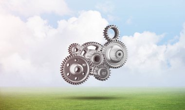 Yeşil çayır üzerinde cogwheels ile soyut mekanizma. İnşaat ve üretim. Mekanik teknoloji makine mühendisliği. Yeşil çimen ve mavi gökyüzü ile doğa manzara. 3b nesneile karışık ortam