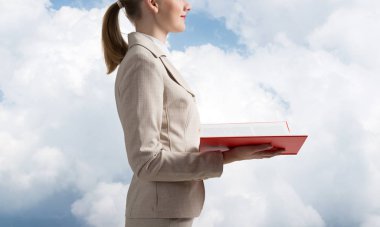 İş kadını, arka planda açık bir defter tutuyor. Profesyonel danışmanlık ve danışmanlık. Kapanış kitabı, kadın ellerinde kırmızı kapaklı. Beyaz takım elbiseli genç kadın..