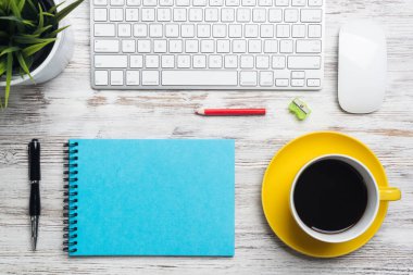 Ofis aksesuarları ile en iyi görünüm konferans masası. İşyerinde mola zamanı. Bilgisayar klavye ve fare, kahve fincan, spiral dizüstü ve tencerede yeşil bitki ile Düz yatıyordu ahşap masa.