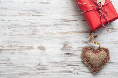 Düz, el yapımı kırmızı kalple hoş bir kompozisyon sergiliyordu. Tahta masadaki kırmızı hediye kutusu. Doğum günün kutlu olsun ya da yıldönümün kutlu olsun. Kopyalama alanı ile romantik aşk hikayesi.