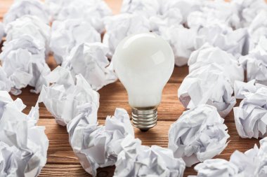 Akkor ampul ve buruşuk beyaz kağıt topları kahverengi ahşap tablo