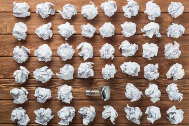 Akkor ampul ve buruşuk beyaz kağıt topları kahverengi ahşap tablo