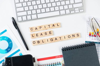 Küpler üzerindeki harflerle birlikte sermaye kiralama yükümlülükleri kavramı. Malzemelerle dolu ofis hayatı. Düz beyaz yüzey, bilgisayar klavyesi ve analiziyle yatıyordu. Sermaye yönetimi ve bankacılık.