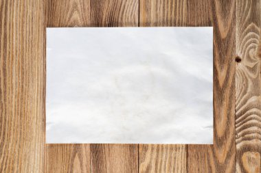 Ahşap masa üzerinde yatan kağıt levha ile Sanatçı işyeri. Boş kopyalama alanı ile dikdörtgen beyaz kağıt. Dokulu doğal ahşap arka plan üst görünümü. Reklam için sanat okulu şablonu