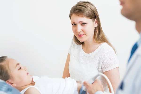 先生超音波は病院で女の子の腹を調べます Sonography機器と診療所での腹腔内診断 密室の女の子のベッドの上に横たわっていた 医療センターの母親と娘 — ストック写真