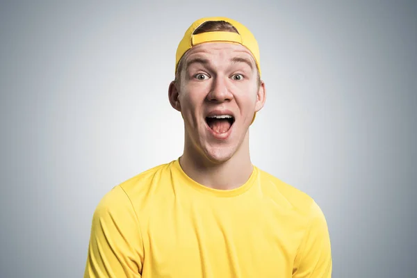 嘴张开的快乐少年 情绪激动的红头发男孩有惊讶的面部表情 男人的画像 穿着黄色T恤 头戴灰色背景的棒球帽 情感和表达概念 — 图库照片